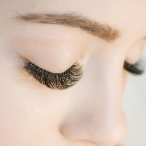 Eyelash extension procedure. Close up view of beautiful woman eyes with long eyelashes. Lengthening lashes for girl in a beauty salon. Beauty concept.