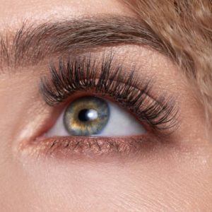 macro shot of woman with green eye and false eyelashes looking up.