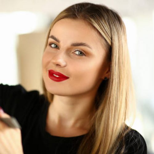 Beautiful Woman Hairdresser Cutting Male Hair. Young Hairstylist Trimming Hairdo. Stylist Holding Scissors for Haircut. Professional Beautician with Red Lips in Beauty Salon Looking at Camera Shot